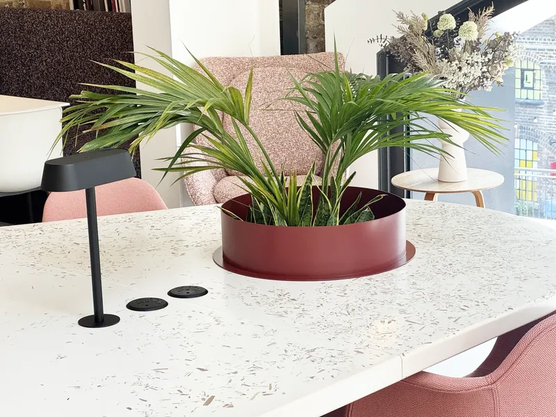 Detail of a REFRAME table with reclaimed flooring top, integrated power and planter